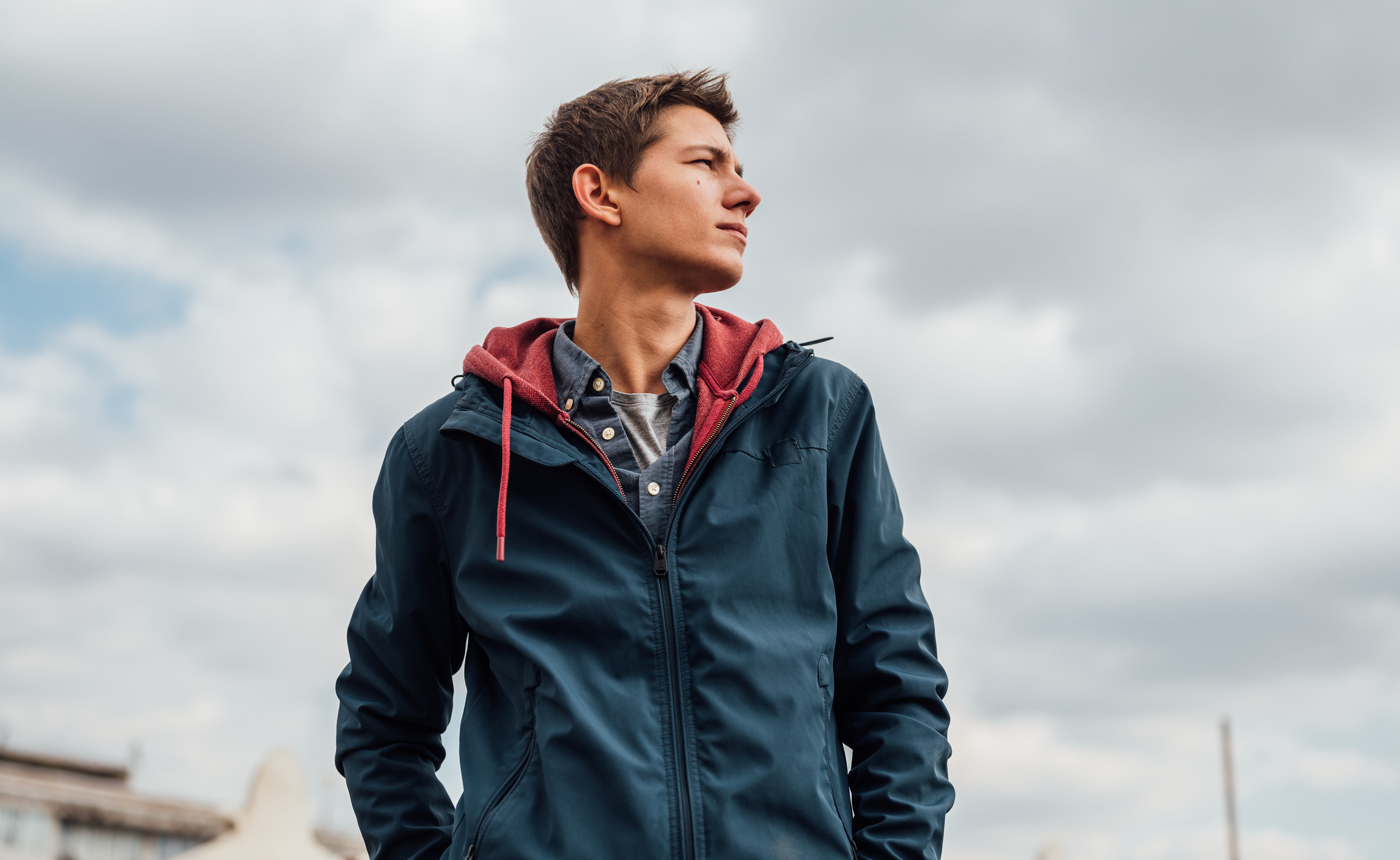 Man pulling a lightweight full-zip jacket on over a heavy hooded sweatshirt