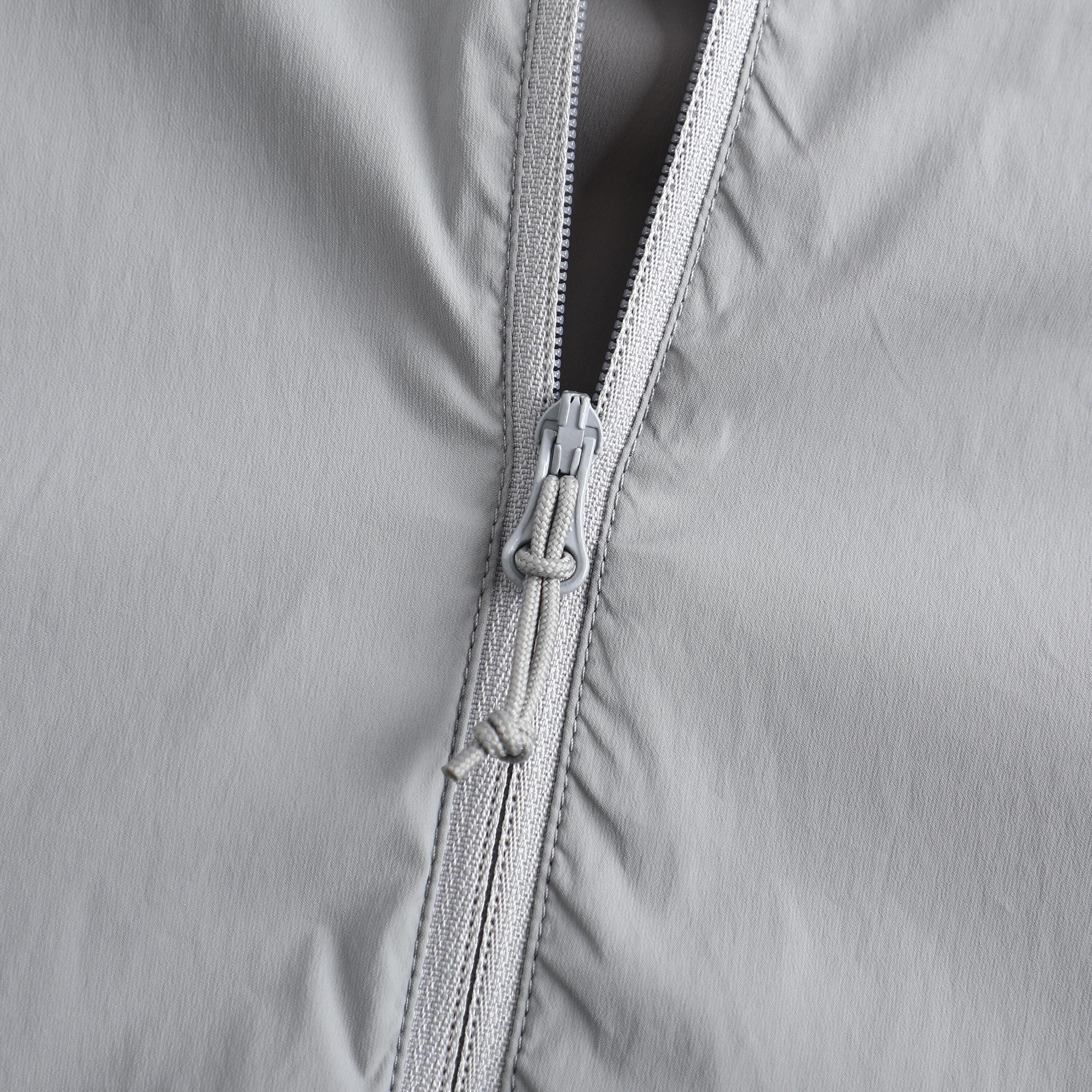 Macro shot of a zipper slider and tape, fingers testing the run one-handed